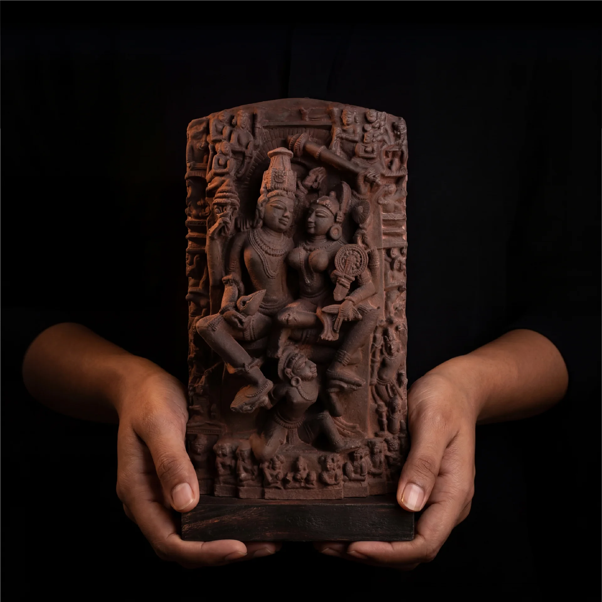 A pair of hands holds a detailed Lakshmi Narayan Sculpture, a stone-finish museum replica featuring intricate 12th-century style carvings.