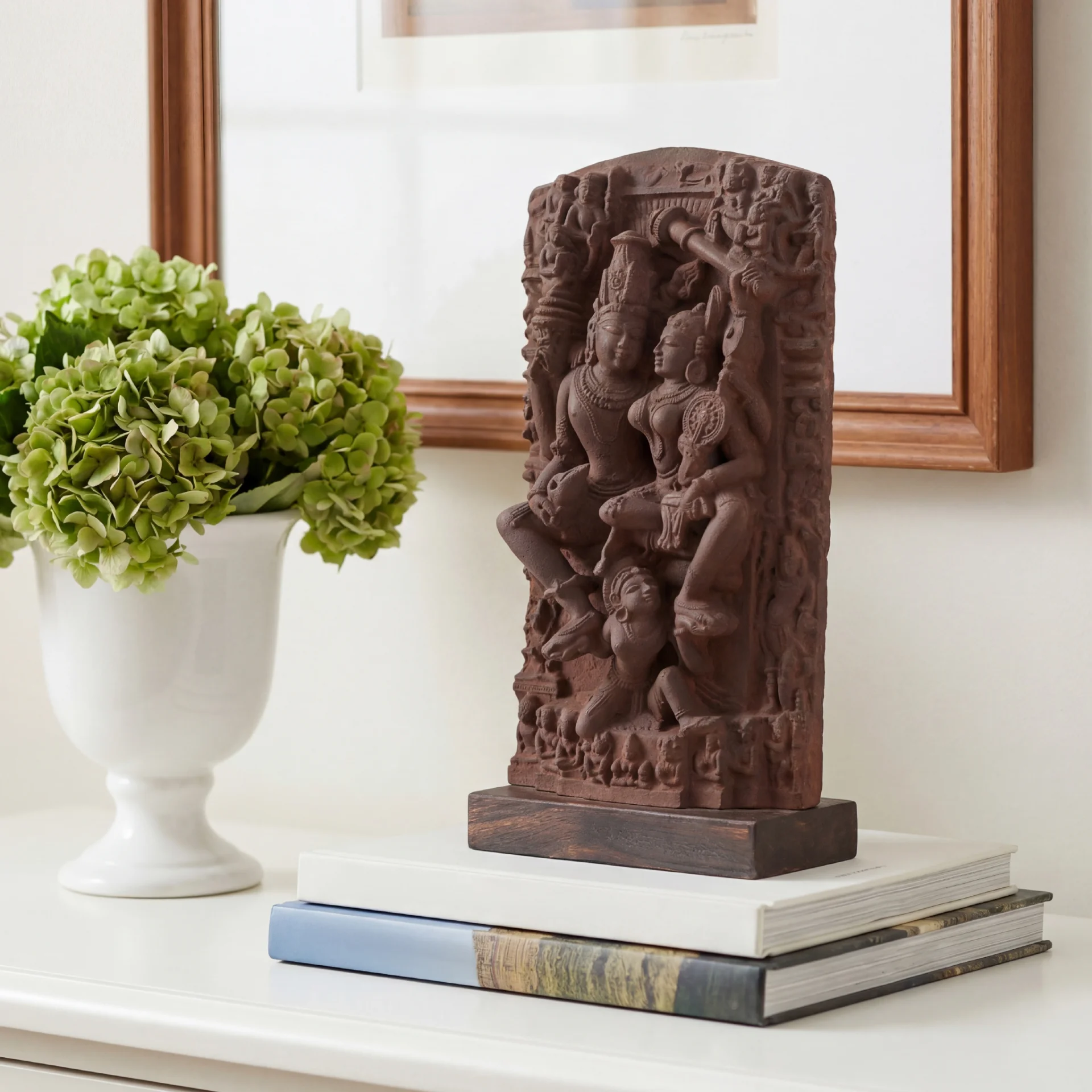 The Lakshmi Narayan Sculpture 9 Inch is displayed on stacked books, featuring intricate hand-finished stone-effect detailing of the deities.