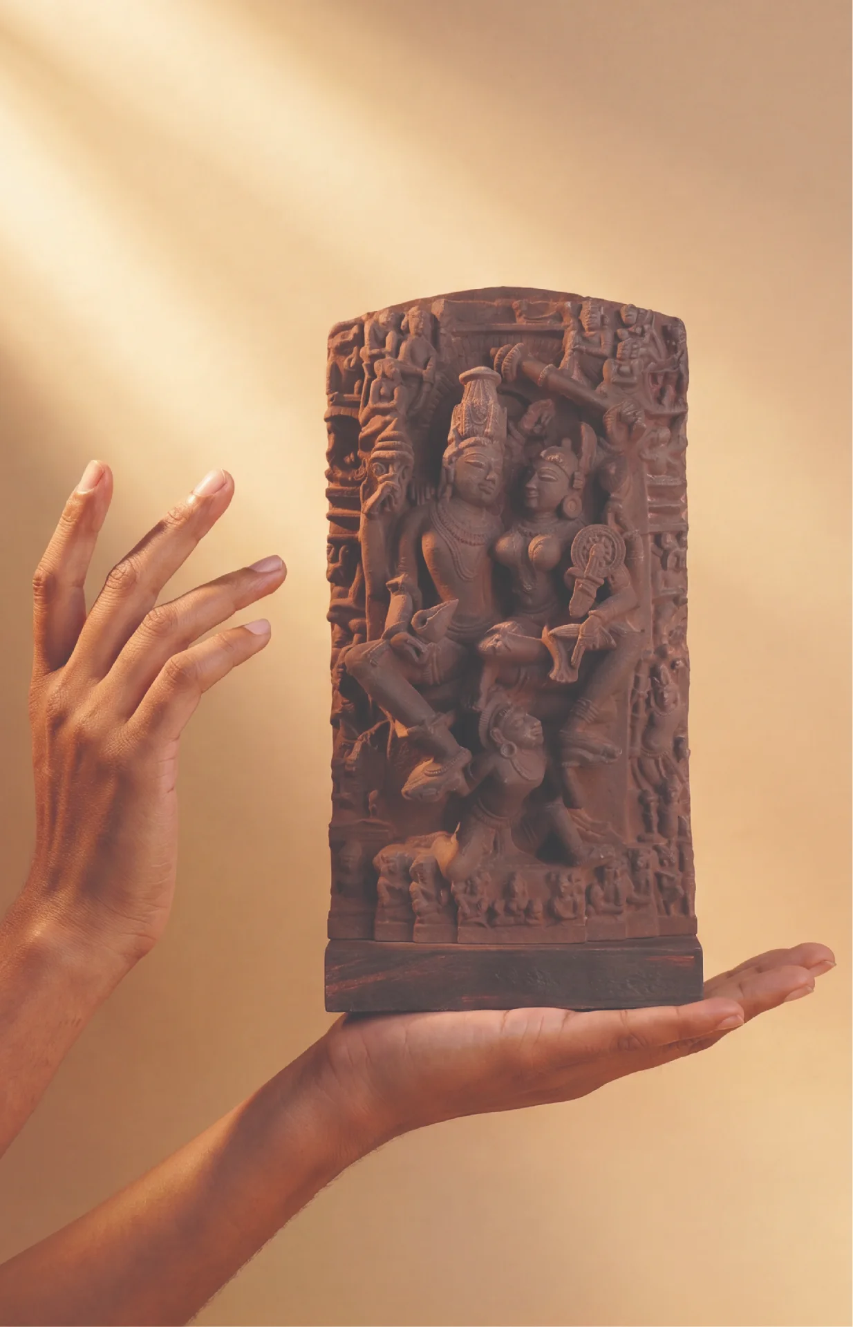 Hands hold a stone composite Lakshmi Narayan Sculpture, showcasing intricate 12th-century medieval iconography against a dark background.
