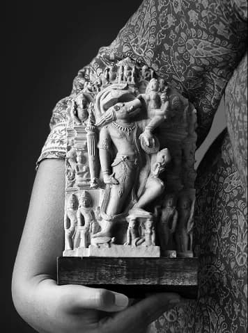 A person holds a detailed Varaha stone replica, showcasing the intricate carved relief of the deity in a museum-quality finish.
