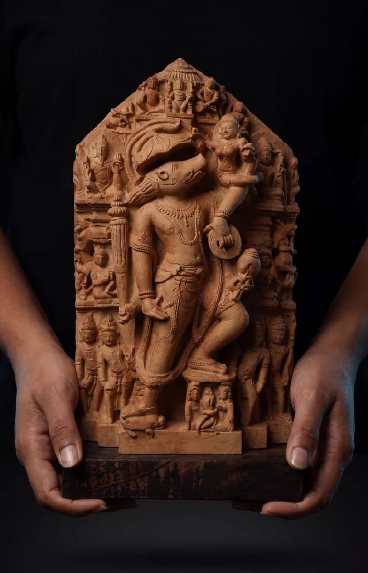 Hands holding a detailed stone composite Nar Varaha Sculpture replica featuring the man-boar deity rescuing Bhudevi in temple art style.