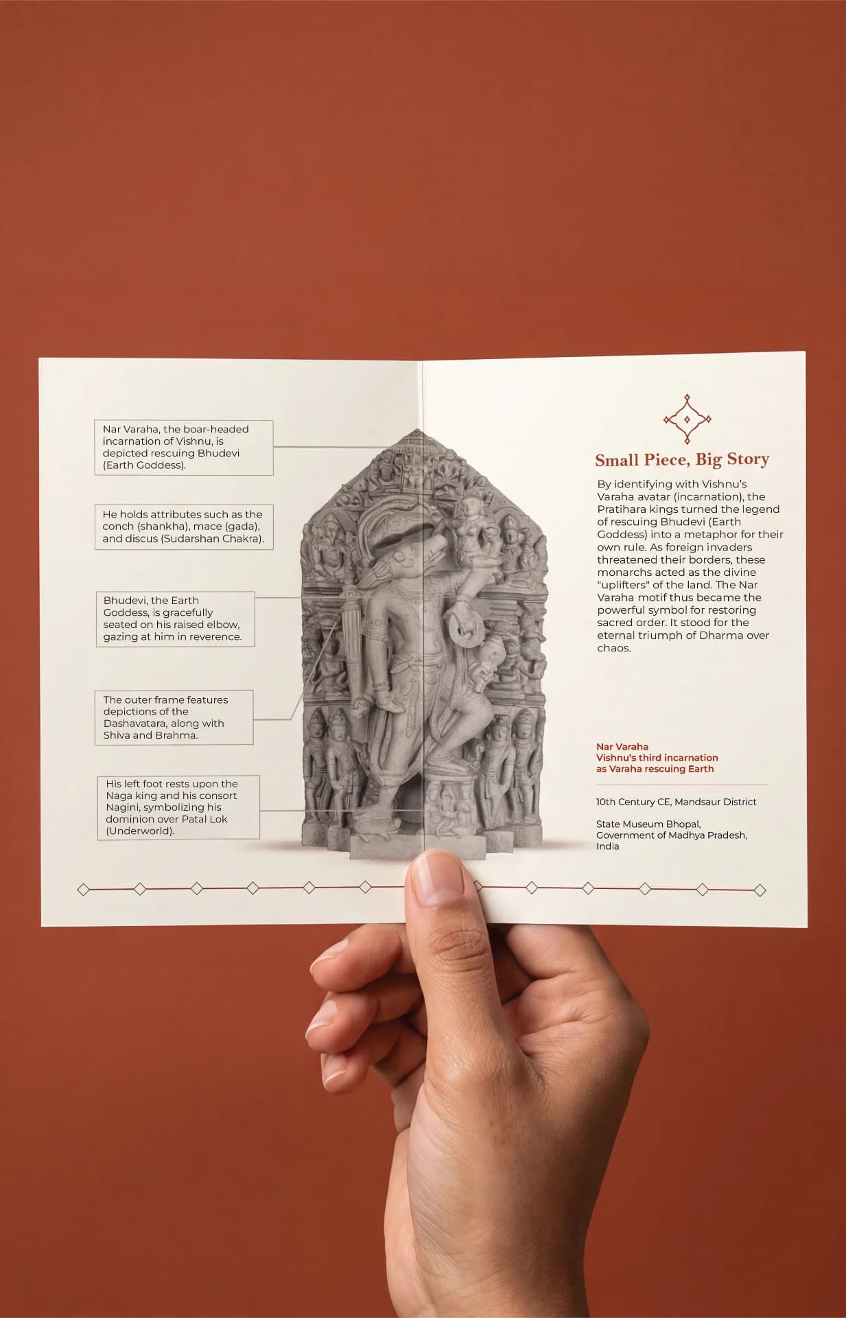 A hand holds an informational brochure featuring the Nar Varaha Sculpture, showcasing detailed stone composite craftsmanship and historical context.