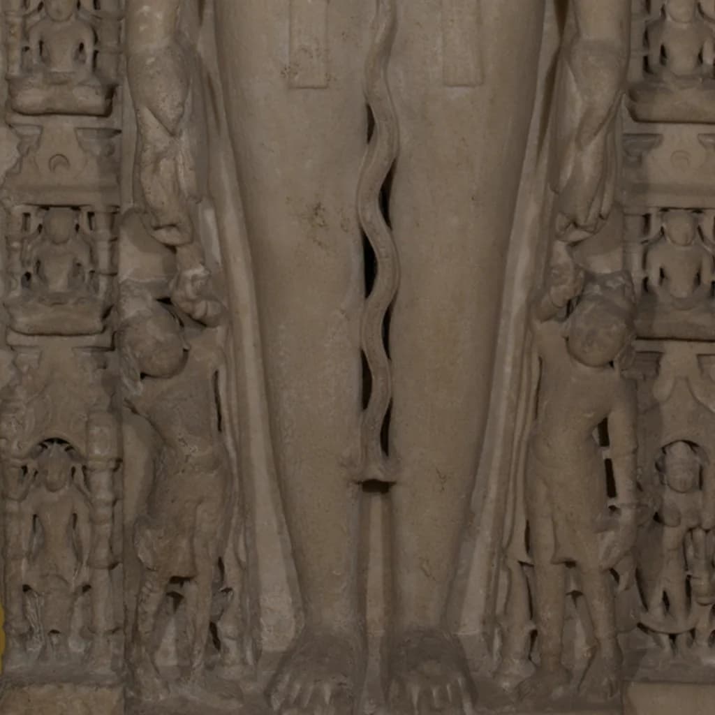 A close-up view of the Parshvanath Sculpture showing the intricate stone composite carvings of the deity's legs and attendant figures.