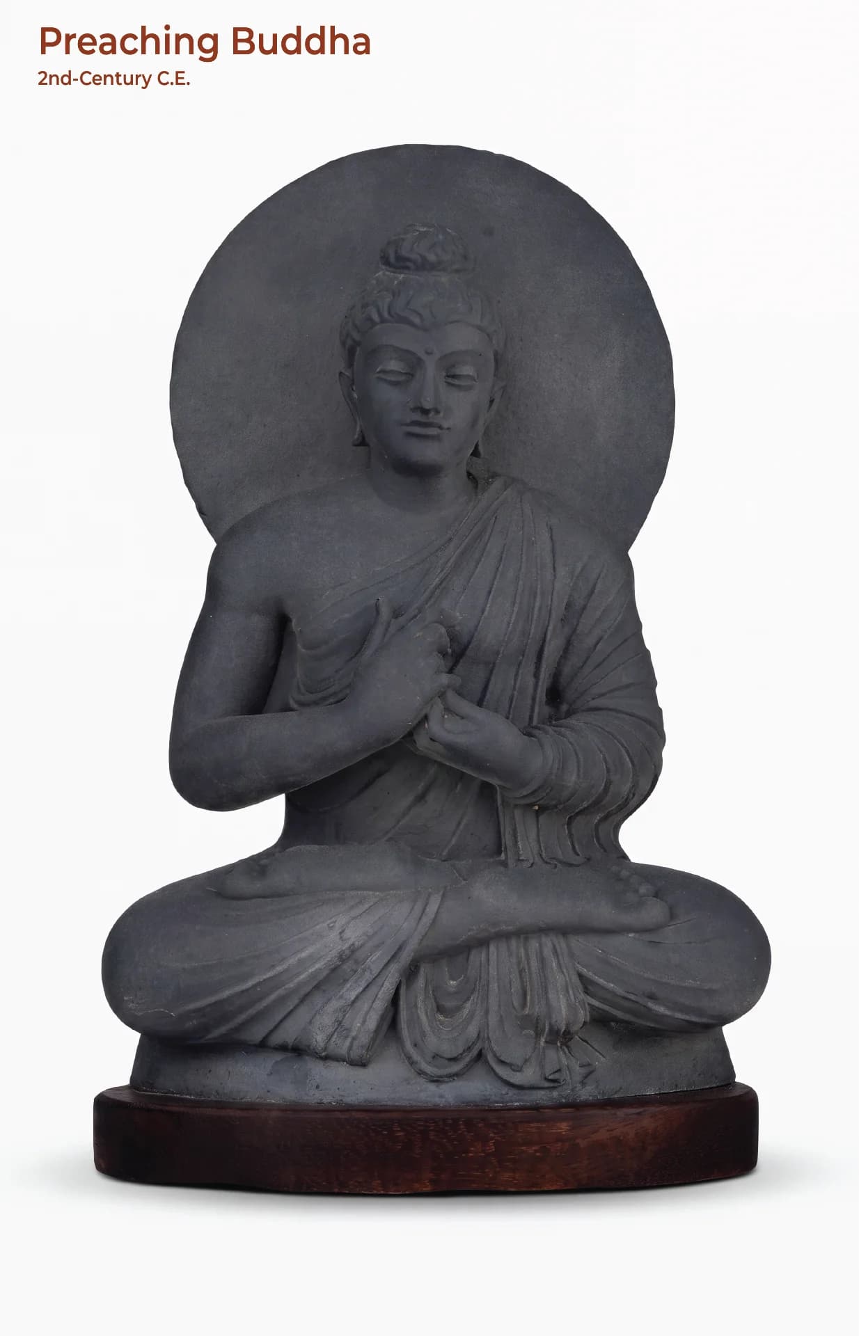 A front-facing view of the Preaching Buddha statue, showcasing its dark stone composite texture and traditional Gandhara art style.