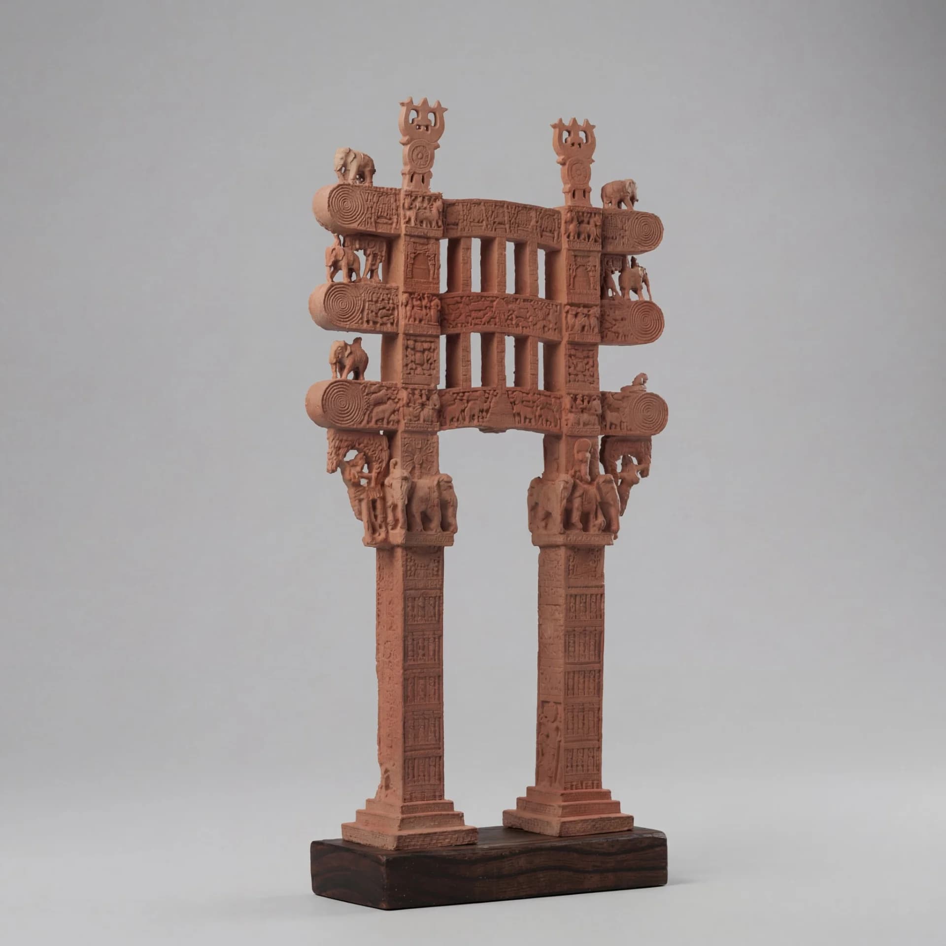 A Sanchi Torana Gateway Miniature replica made of stone composite, featuring intricate carvings on a dark wooden base.