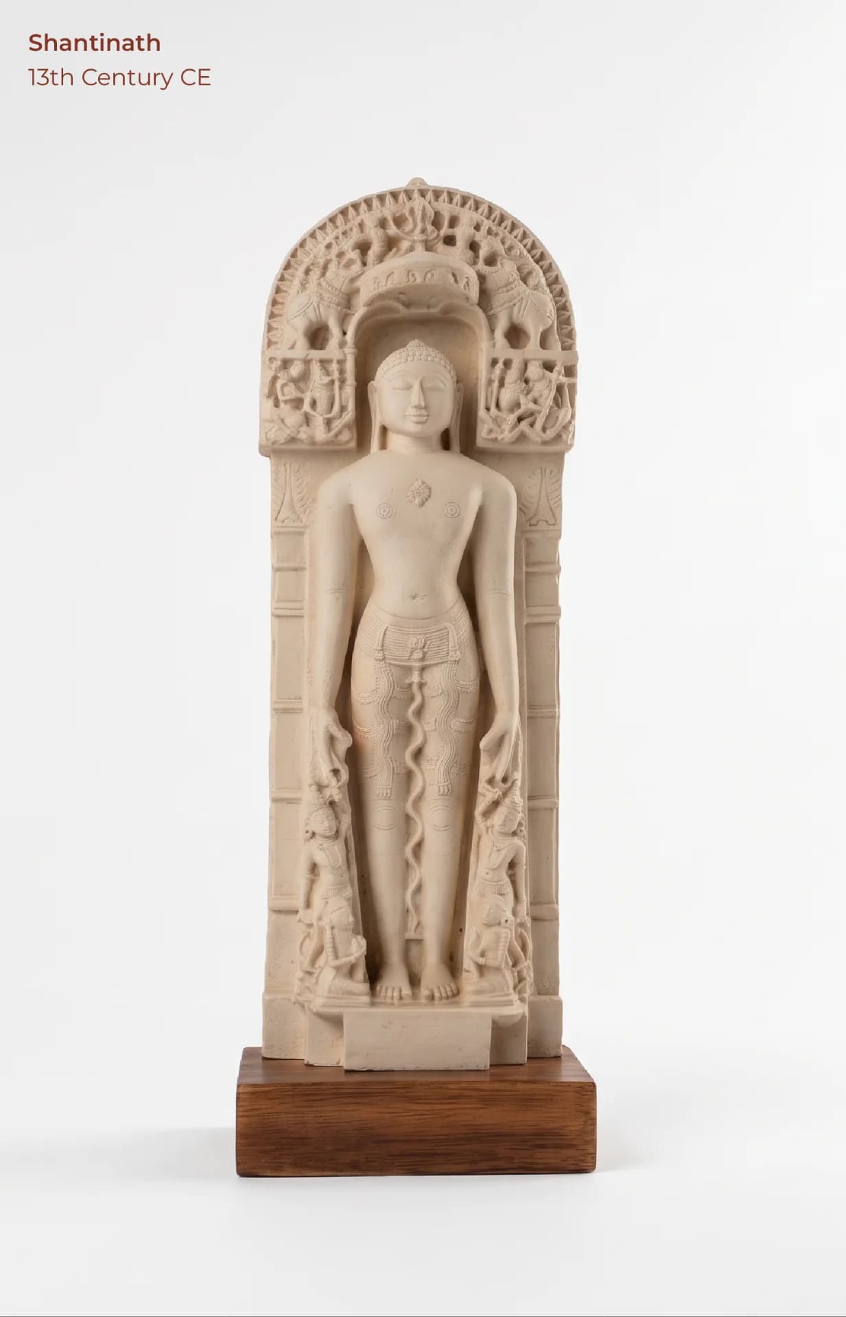 A full-length front view of the Shantinath Sculpture, a marble museum replica featuring intricate carvings and a wooden base.