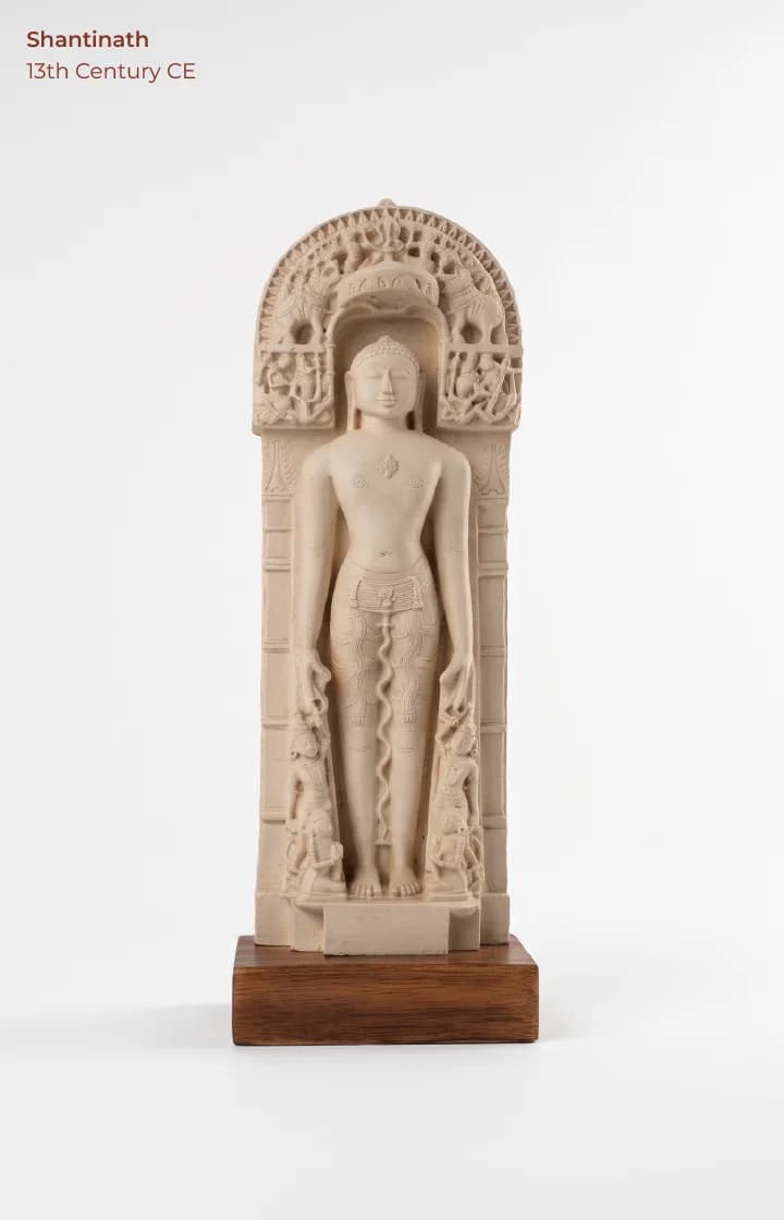 A full-length front view of the Shantinath Sculpture, a detailed marble-finish museum replica featuring intricate arched carvings.