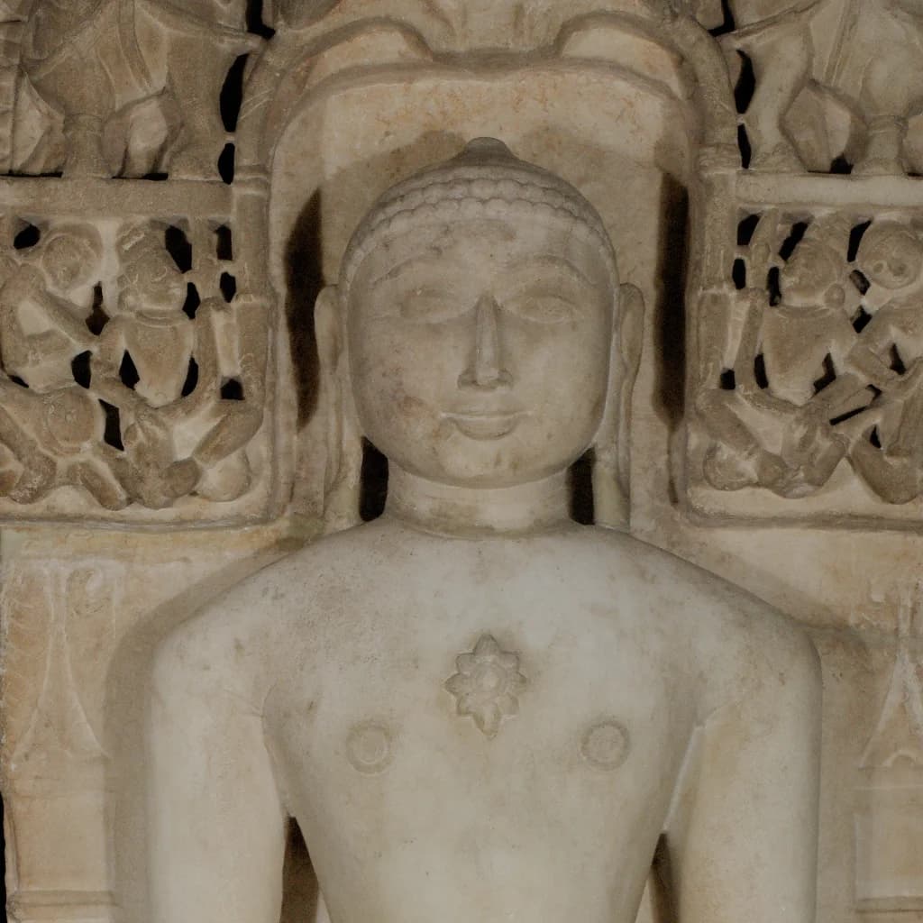 A close-up view of the Shantinath Sculpture, showcasing the serene marble face and intricate carved lattice background details.